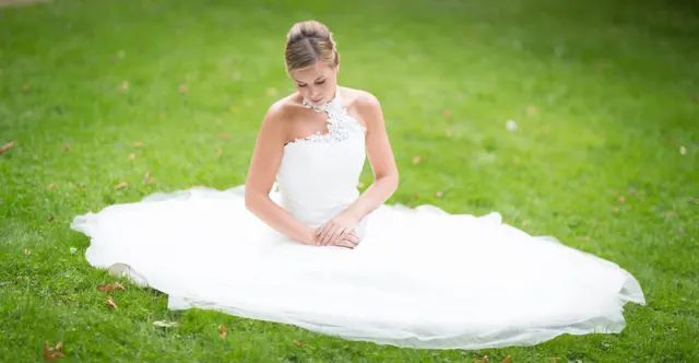 Mariée assise dans l’herbe, robe étalée – photographe de mariage à Reims