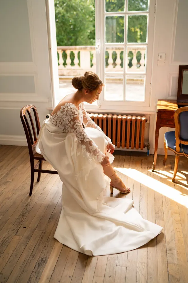 Mariée assise près d'une fenêtre pendant les préparatifs – Frédéric Leroux, photographe de mariage à Reims