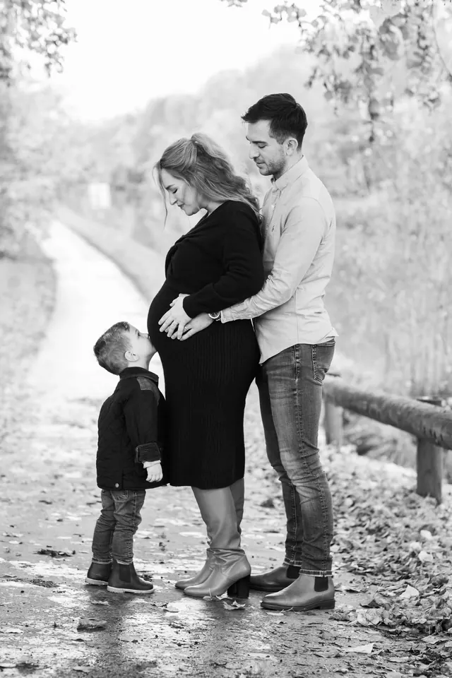 Séance grossesse en famille : le grand frère embrasse le ventre de maman, en noir et blanc – Frédéric Leroux, photographe à Reims